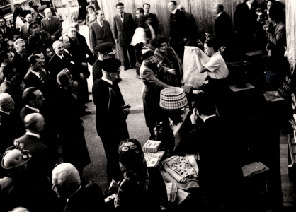 King Paul and queen Frederica visiting the Double Axe stand in the Athens 1949 folk art exhibition. Kaloutsi&amp;amp;#039;s daughter, Sissi, shows a tablecloth.